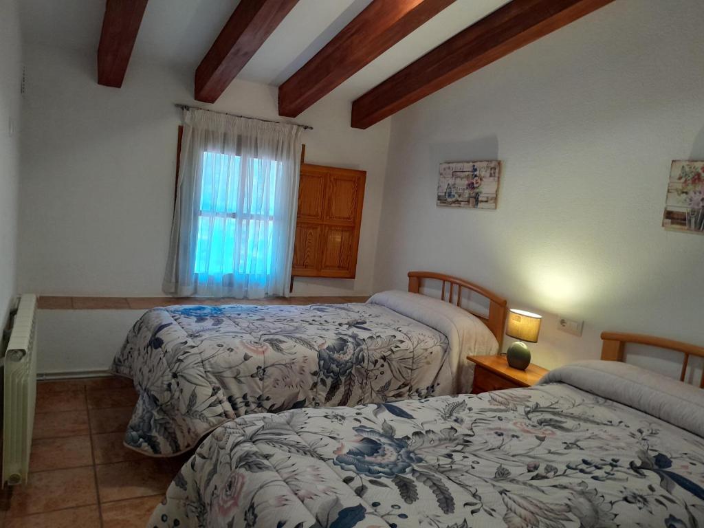 1 dormitorio con 2 camas y ventana en Casa Manolita, en La Pobla de Benifassà (Puebla de Benifasar)