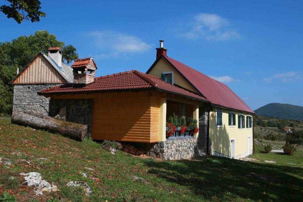 Kuća za odmor Valinčić في Brinje: منزل صغير بسقف احمر على تلة
