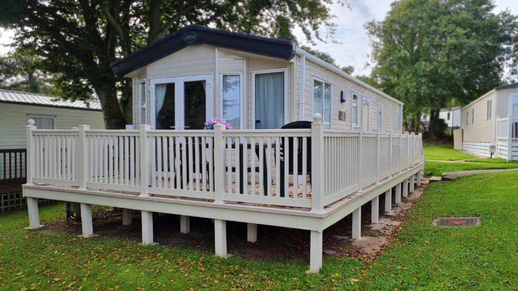 a small white house with a porch on a yard at Stunning 2 Bed Static Caravan at Hoburne Devon Bay in Goodrington