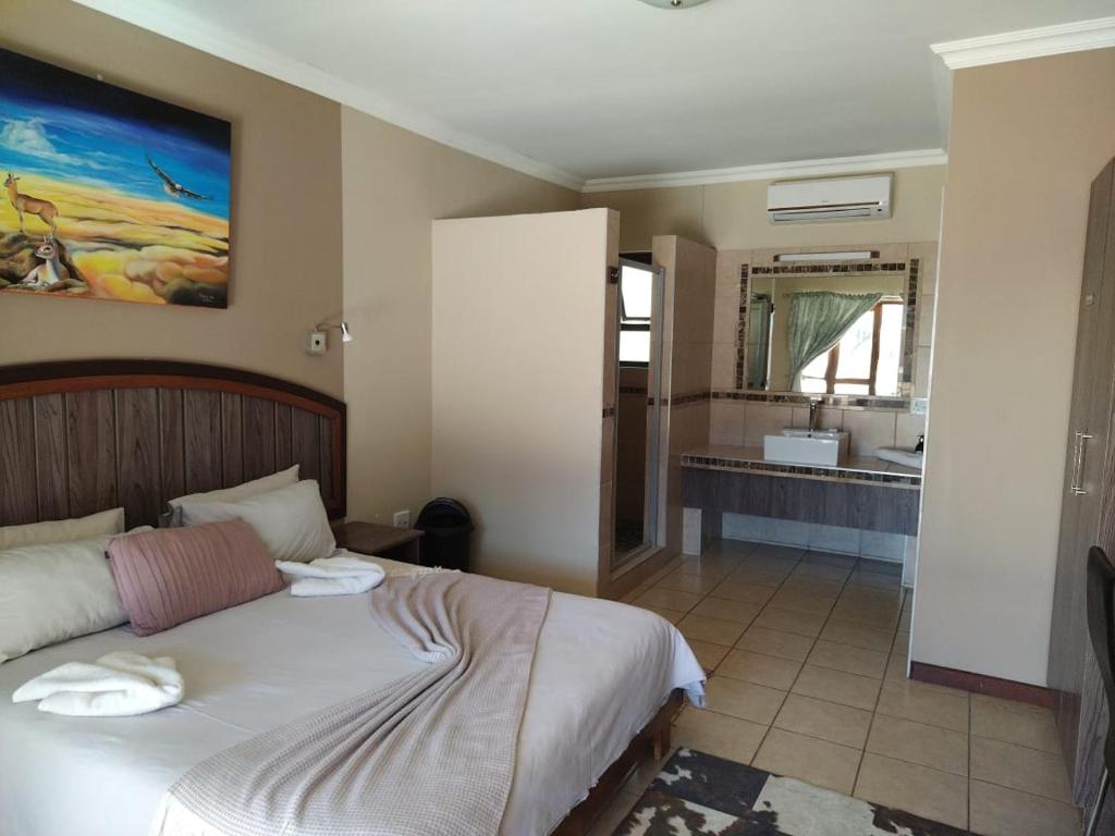 a bedroom with a bed and a bathroom with a sink at Goba Lodge in Gobabis