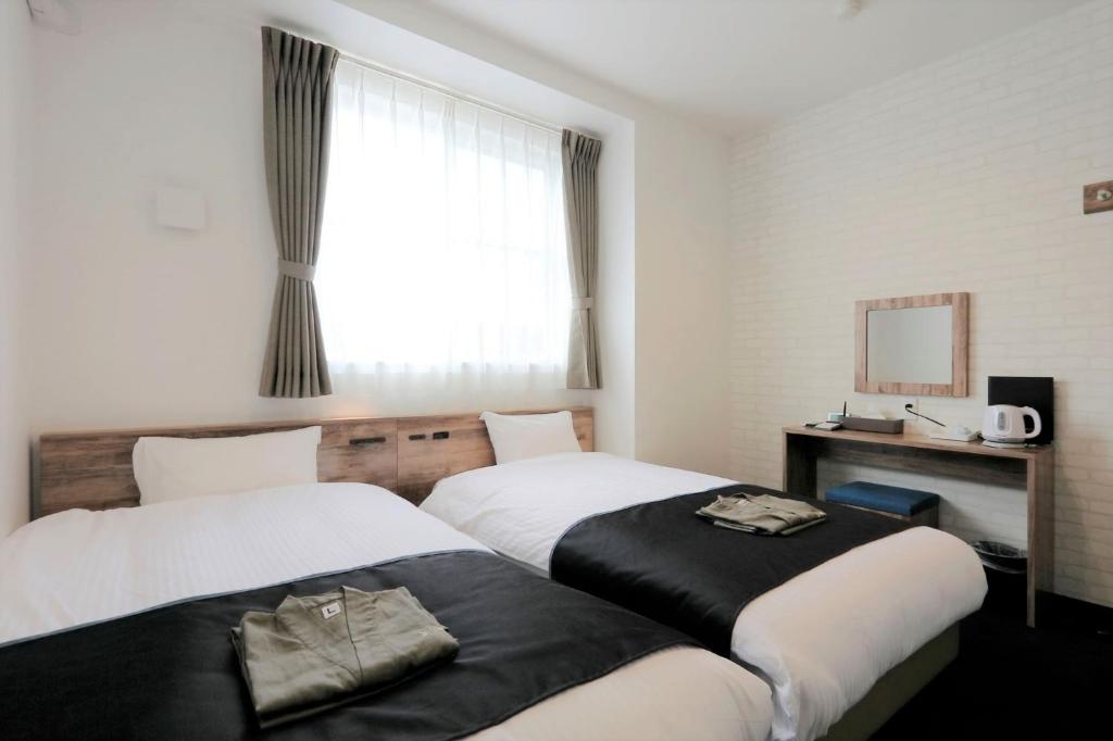 una camera d'albergo con due letti e una finestra di Yorimichi no Yado - Vacation STAY 37453v a Toki