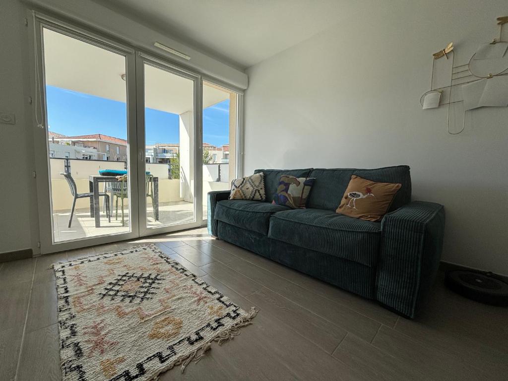 d'un salon avec un canapé et un balcon. dans l'établissement Charmant T2 avec piscine, à La Londe-les-Maures