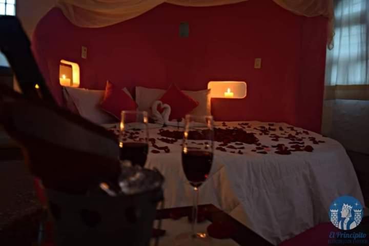 ein Schlafzimmer mit einem Bett mit zwei Gläsern Wein in der Unterkunft Parejas in La Orilla