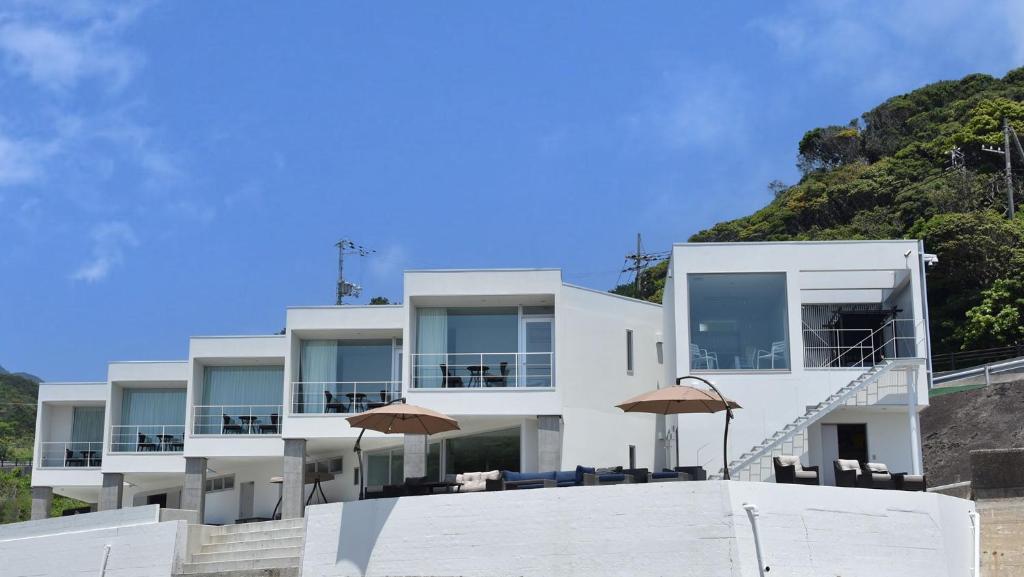 Beach Terrace Kushimoto - Vacation STAY 37415v في Wabuka: مبنى أبيض فيه مظلات أمامه