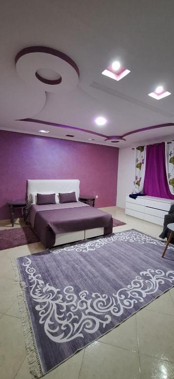 a bedroom with a bed and a purple wall at Super Cozy Apartment in Larache