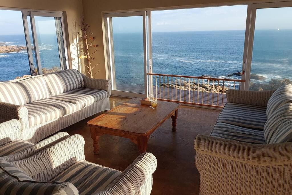 ein Wohnzimmer mit Sofas, einem Tisch und Meerblick in der Unterkunft Rusenvrede Self Catering in Cape St Francis