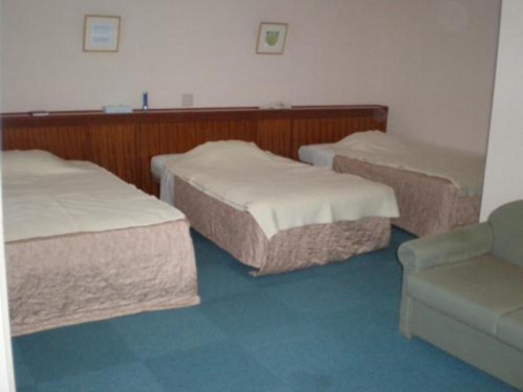 ein Zimmer mit 3 Betten und einem Sofa darin in der Unterkunft Kikai Daiichi Hotel - Vacation STAY 30433v 