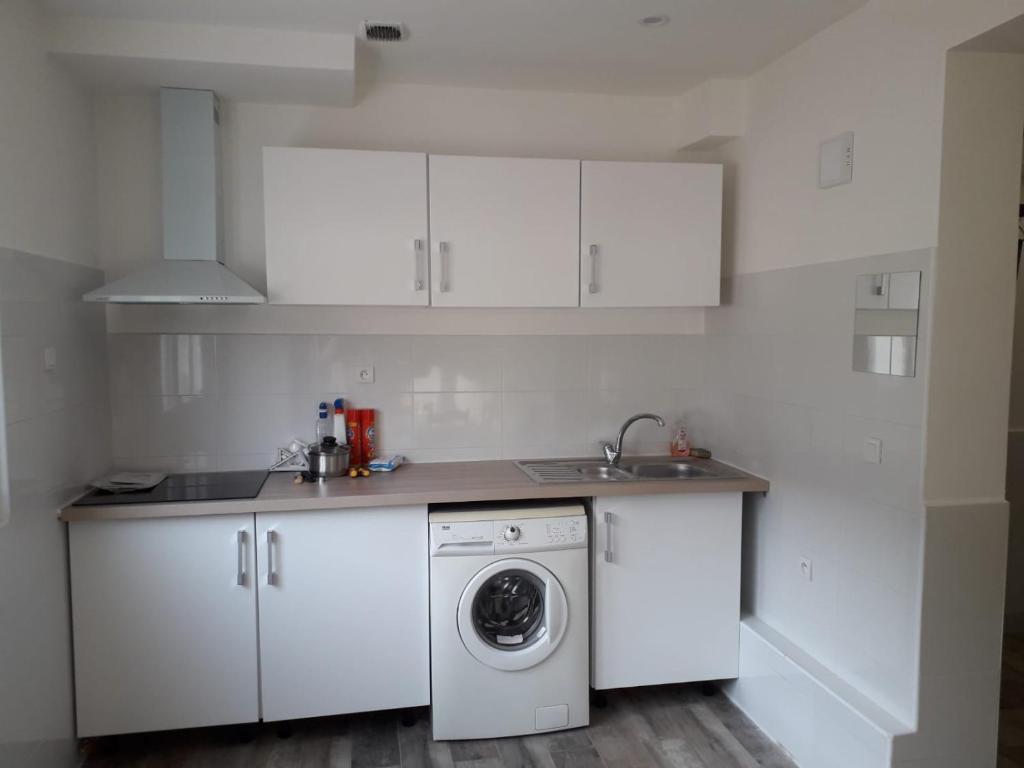 een witte keuken met een wasmachine en een wastafel bij 143 VH in Le Blanc-Mesnil