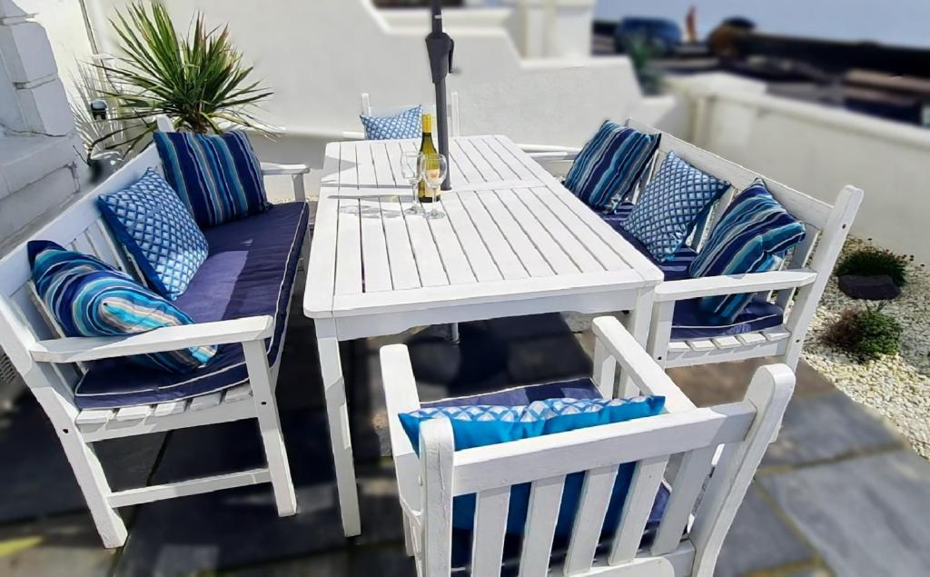 サンドゲートにあるBeach View, A Stunning 4 Bedroom House Opposite The Sea! Sleeps 10! Families, Friends, Contractors and Pets Welcome!のパティオに置かれた白いテーブルと椅子、そして青い枕