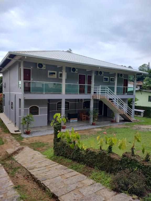 a house with a balcony and a yard at Pousada Recanto Família in Paraty