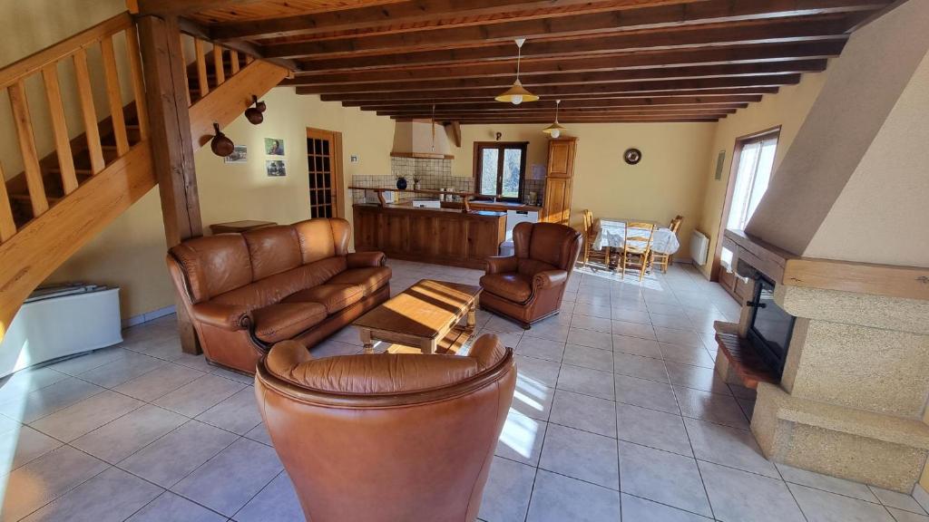 een woonkamer met lederen meubels en een trap bij Les Mésanges - Jardin - Nature in Agnat