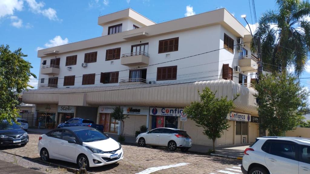 un edificio bianco con macchine parcheggiate di fronte di Flat ao lado do Shopping a Santa Cruz do Sul