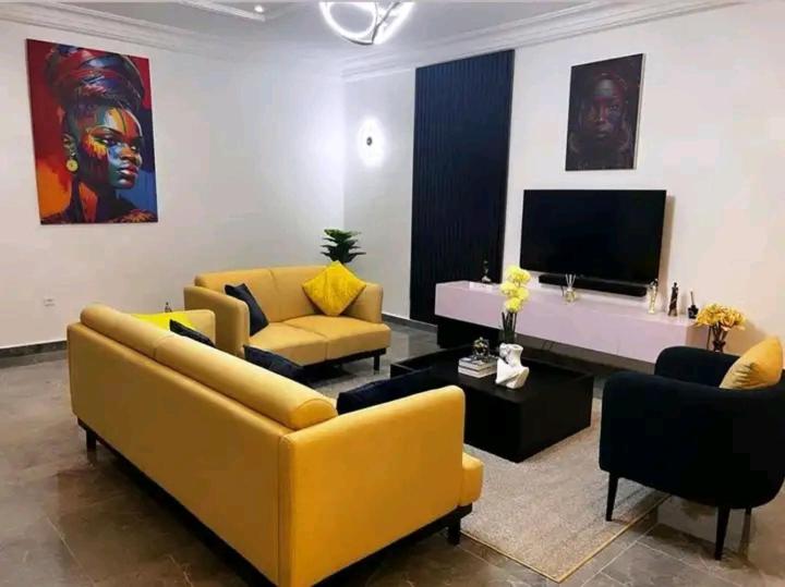 uma sala de estar com sofás amarelos e uma televisão de ecrã plano em Luxe akpakpa em Agbato