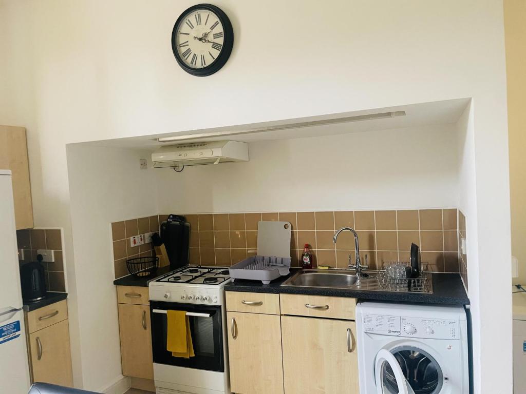 a kitchen with a sink and a clock on the wall at Bustling Western Apartment in London