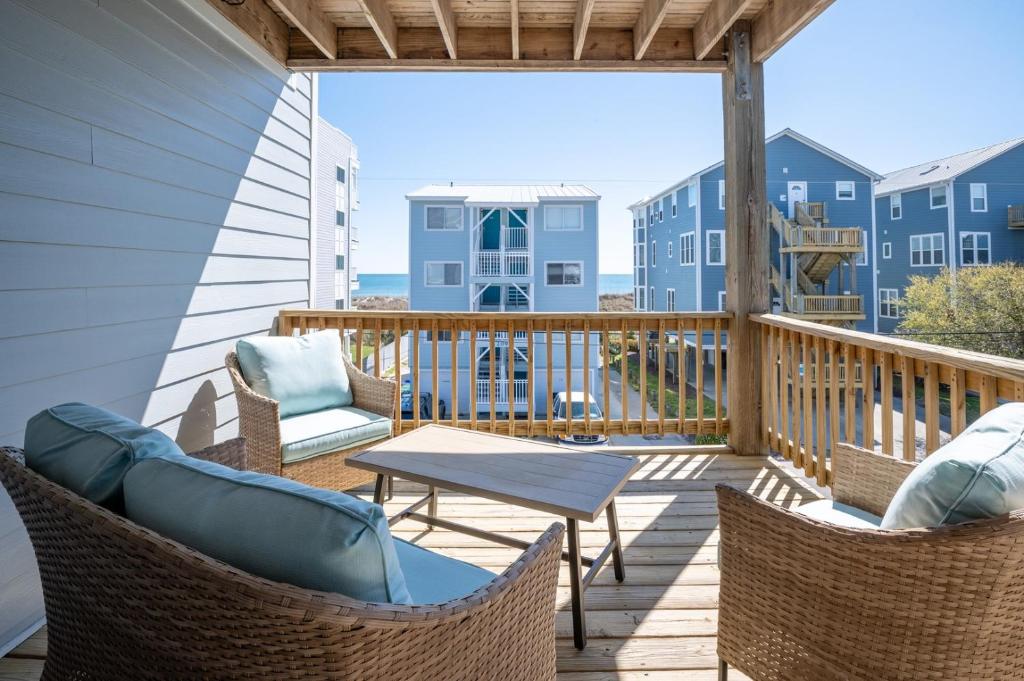 a balcony with chairs and a table with a view of the ocean at Oceanview Condo Near the Boardwalk - Sea Drift Hawks Nest in Carolina Beach