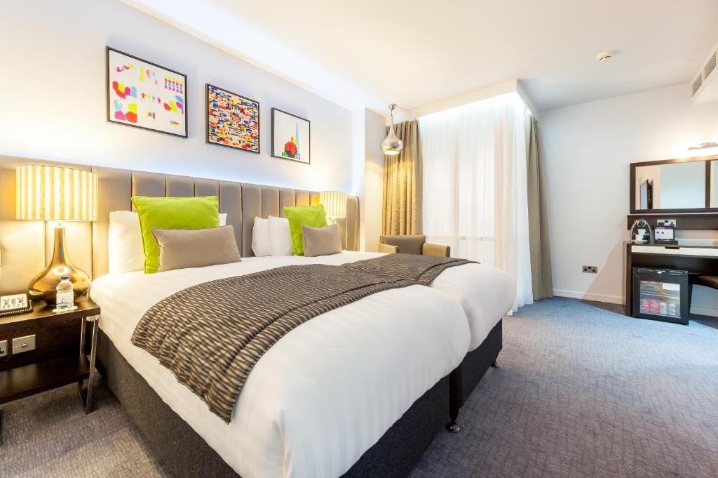 a bedroom with a large bed with green accents at Mercure London Paddington Hotel in London