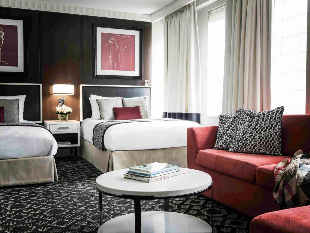 a hotel room with two beds and a couch at Sofitel Lafayette Square Washington DC in Washington, D.C.