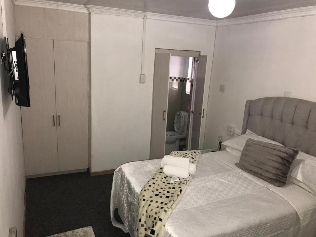 een slaapkamer met een bed met een zwart-witte kap bij Alizwa Guesthouse in East London