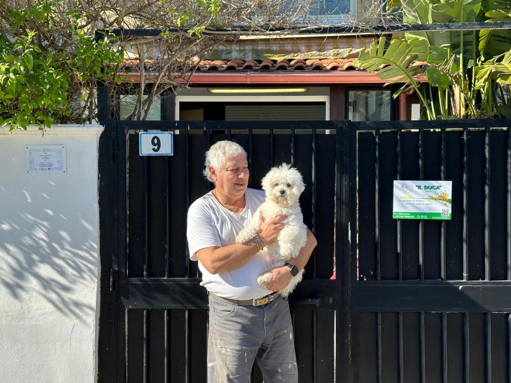un hombre sosteniendo un perro blanco delante de una puerta en Il Duca, en San Cataldo