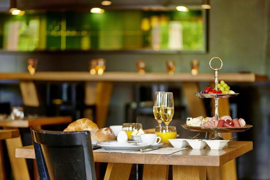 a table with a plate of food and glasses of wine at Sorell Hotel Rigiblick - Studios & Spa Suites in Zürich