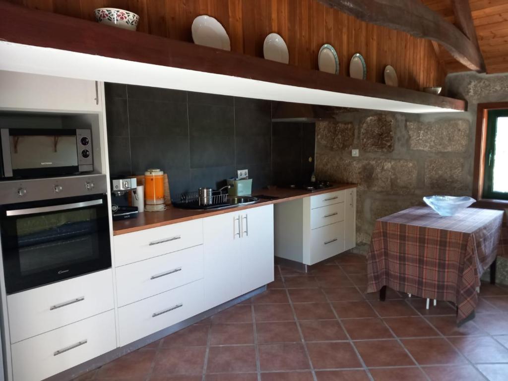 cocina con armarios blancos y fogones en Casa de Andrães - Glicíneas, en Marco de Canaveses