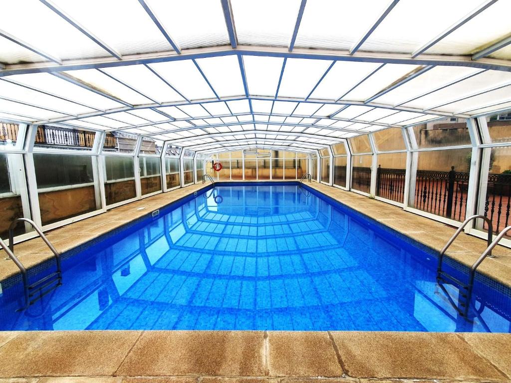 a large indoor swimming pool with blue water at Apartamentos SOL Y PLAYA Foz in Foz