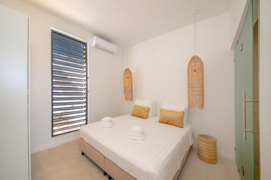a white bedroom with a bed and a window at Villa NOMA - Apartment w/ Lovely View I 5 min/Beach I Free SUP in Willemstad