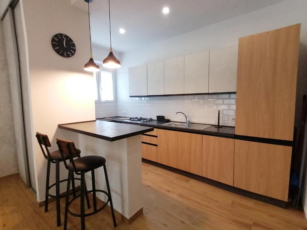 a kitchen with a counter and stools and a clock at Urban Loft in Lido di Ostia