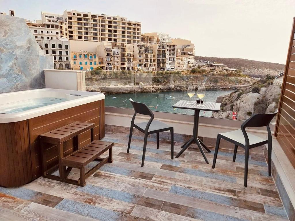 a bath tub on a balcony with a view of a city at Blu Waters Boutique Hotel in Xlendi