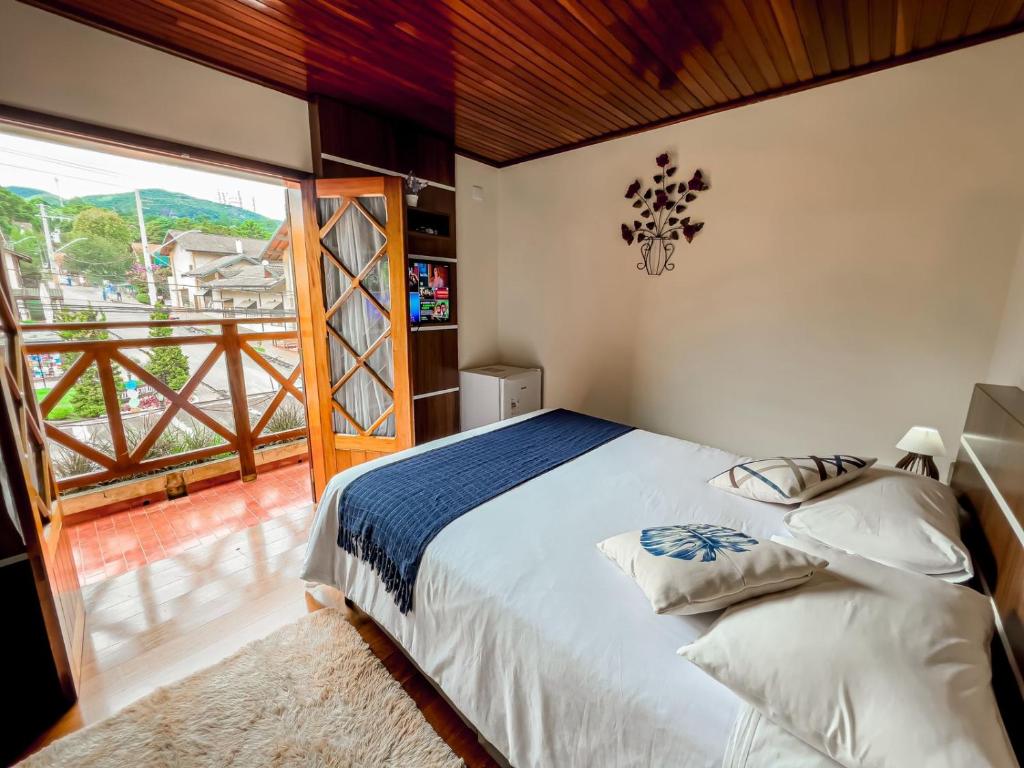 a bedroom with a bed and a large window at Pousada Avenida in Monte Verde