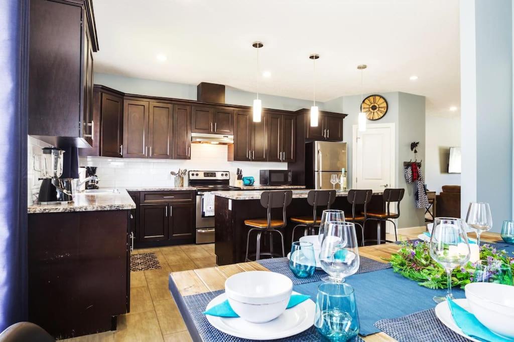 a kitchen with a table with plates and wine glasses at Modern Home - King Bed - Garage - Long Stays in Edmonton
