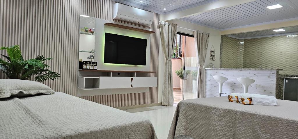 a bedroom with a tv on the wall and two beds at Loft da Figueira, Abraão Ilha Grande. in Angra dos Reis