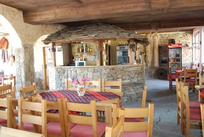 um restaurante com uma mesa e cadeiras e uma parede de pedra em Комитите em Troyan