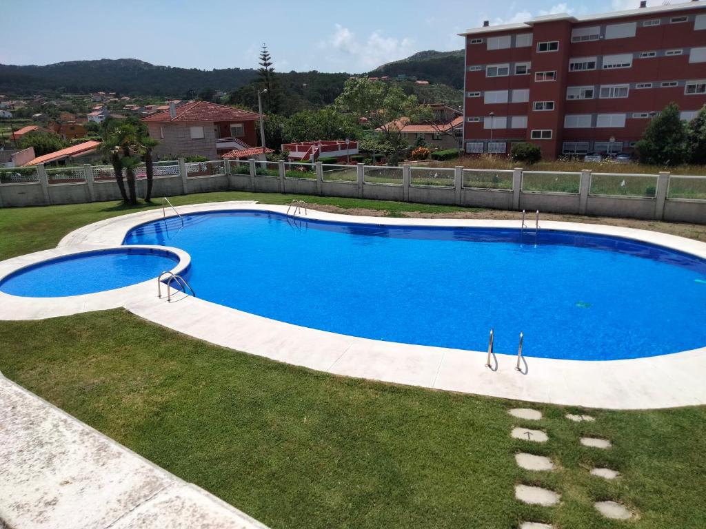 a large blue swimming pool in a yard with buildings at O Recuncho de Belén in Baiona