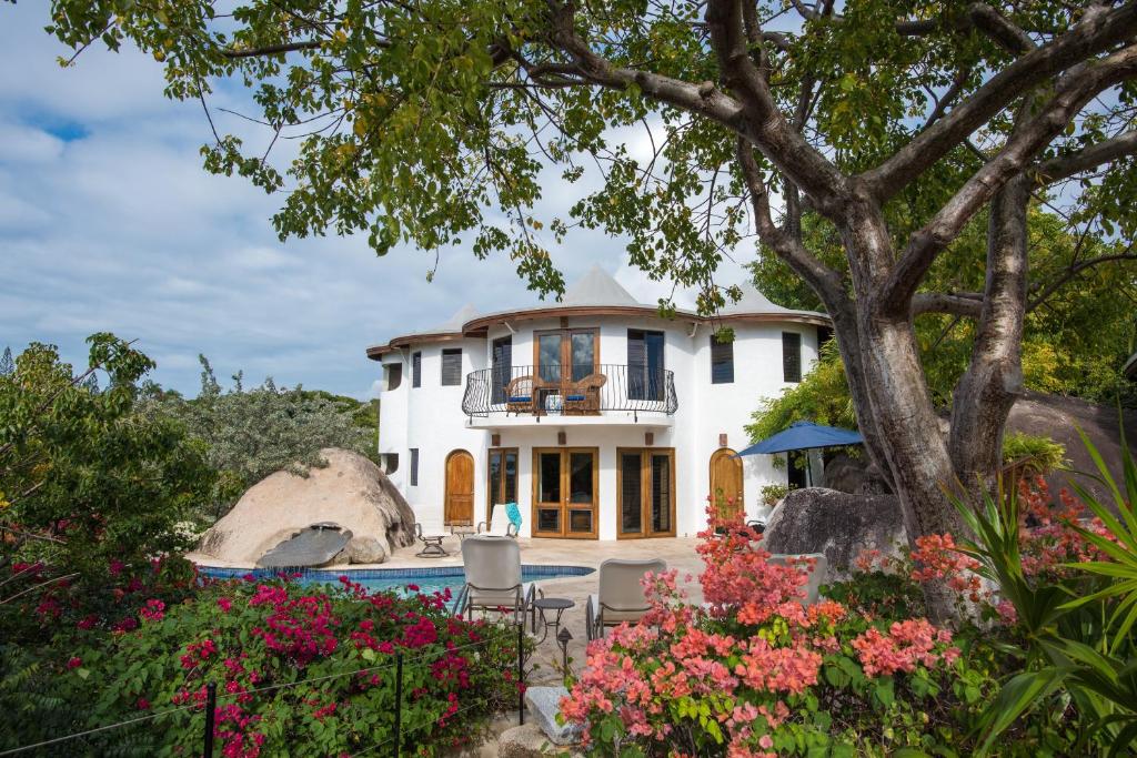 a white house with a tree and flowers at On The Rocks Villa in Spanish Town