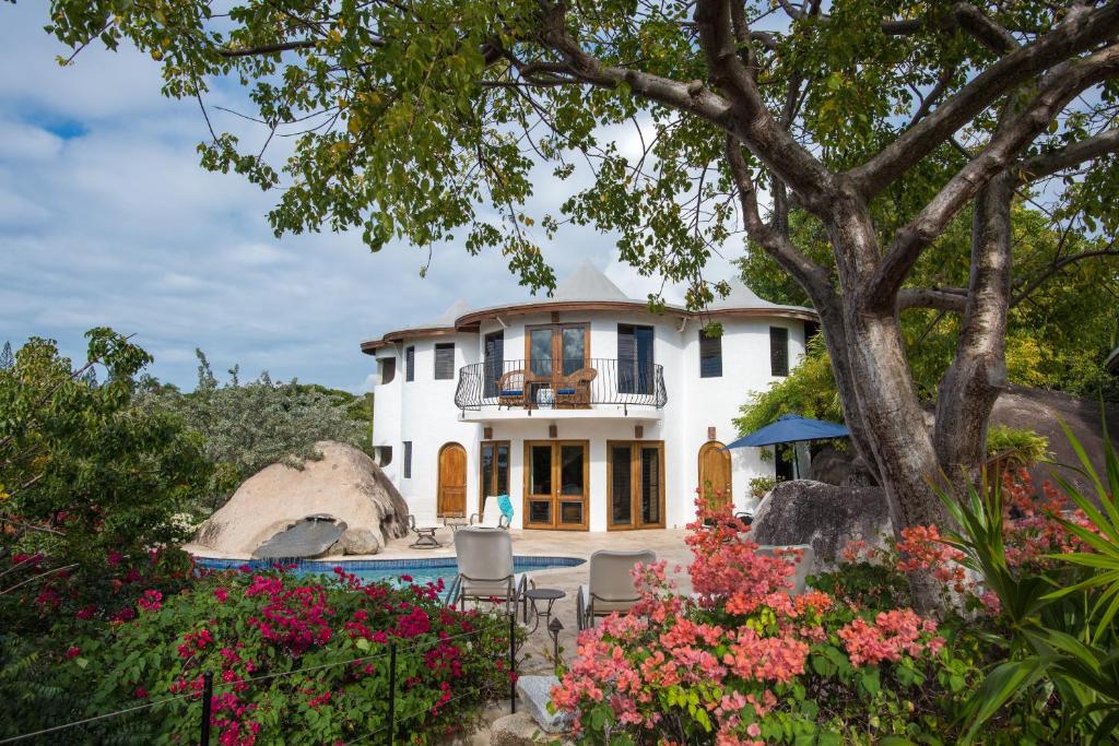 una casa blanca con un árbol y flores en On The Rocks Villa, en Spanish Town