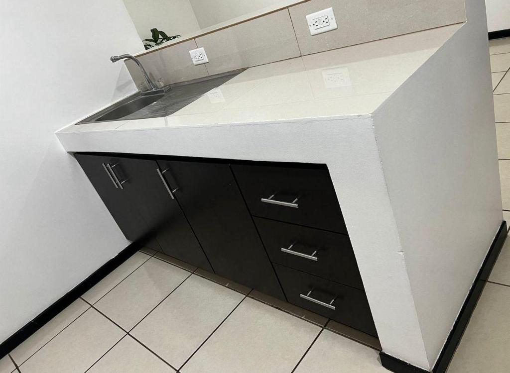 a kitchen counter with a sink and black cabinets at ALAJUELA, Prívate Room,Hermosa Madre in Alajuela