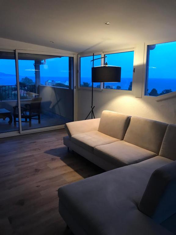 un salon avec un canapé blanc devant les fenêtres dans l'établissement Appartement villa toit terrasse, à Menton