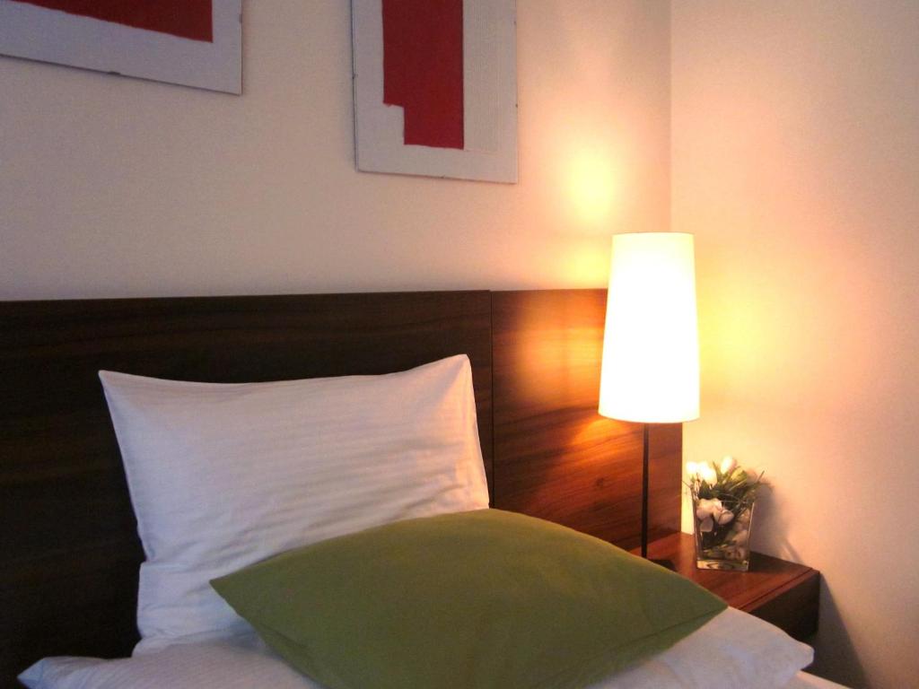 a bed with a white pillow next to a lamp at Penzion Luxor in Trnava