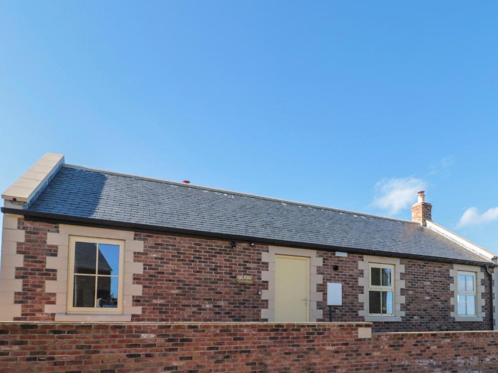 a red brick house with a gray roof at Glebe Cottage in Alnwick