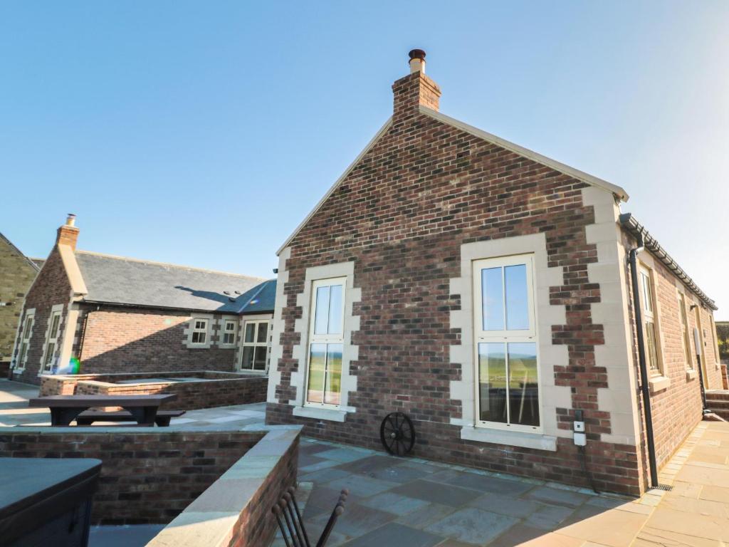 un edificio in mattoni con panchina su un patio di Bothy Cottage ad Alnwick