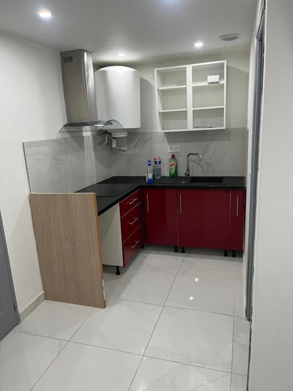 a kitchen with red cabinets and a sink at Appartement calme dans villa individuelle in Bagnols-sur-Cèze