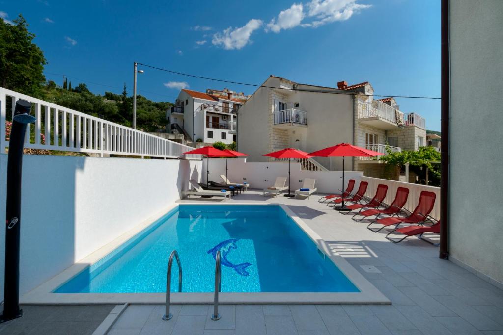 a swimming pool on a balcony with red umbrellas at Apartments BINGO in Cavtat