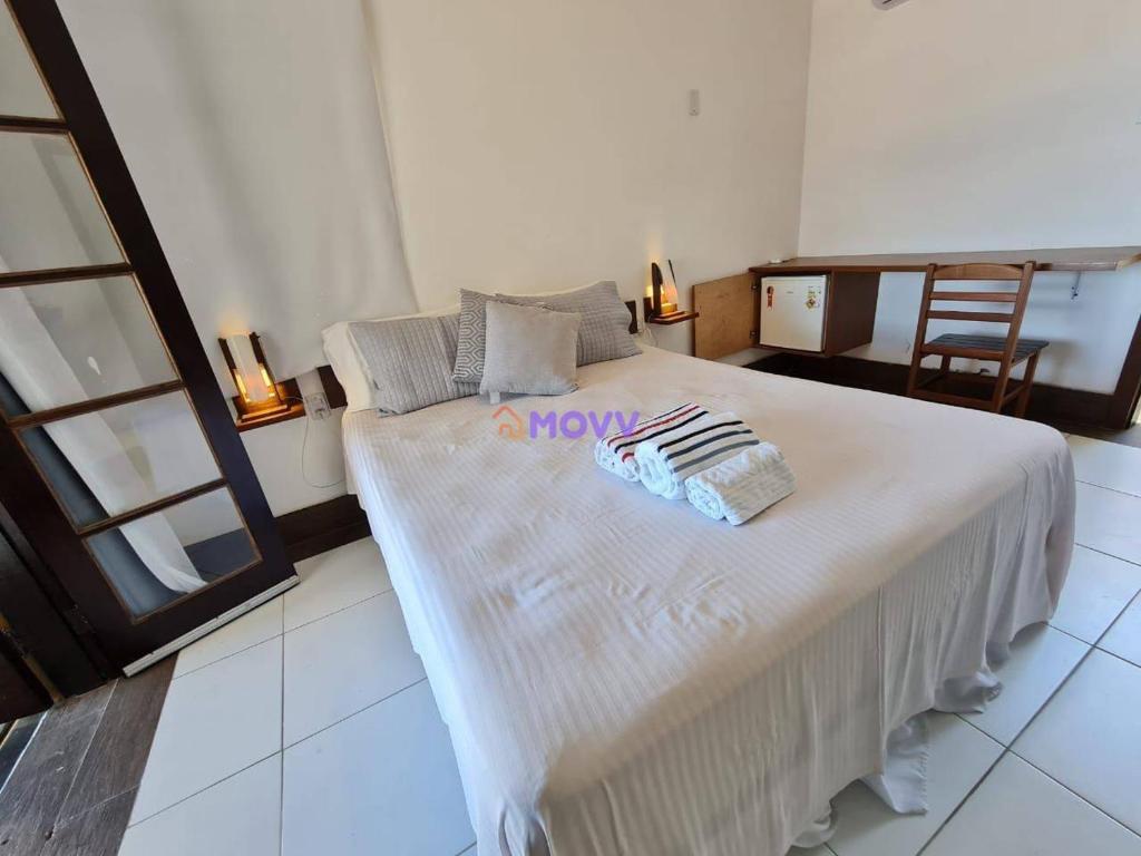 ein großes weißes Bett in einem Zimmer mit einem Tisch in der Unterkunft CAMBOINHAS BnB in Niterói