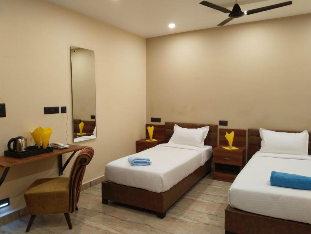 a room with two beds and a desk and a mirror at Hotel Windsor Plaza in Hyderabad