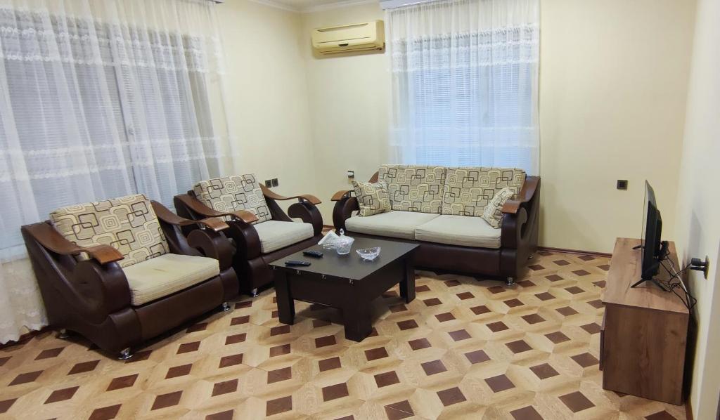 a living room with chairs and a tv and a table at Pink house in Lankaran