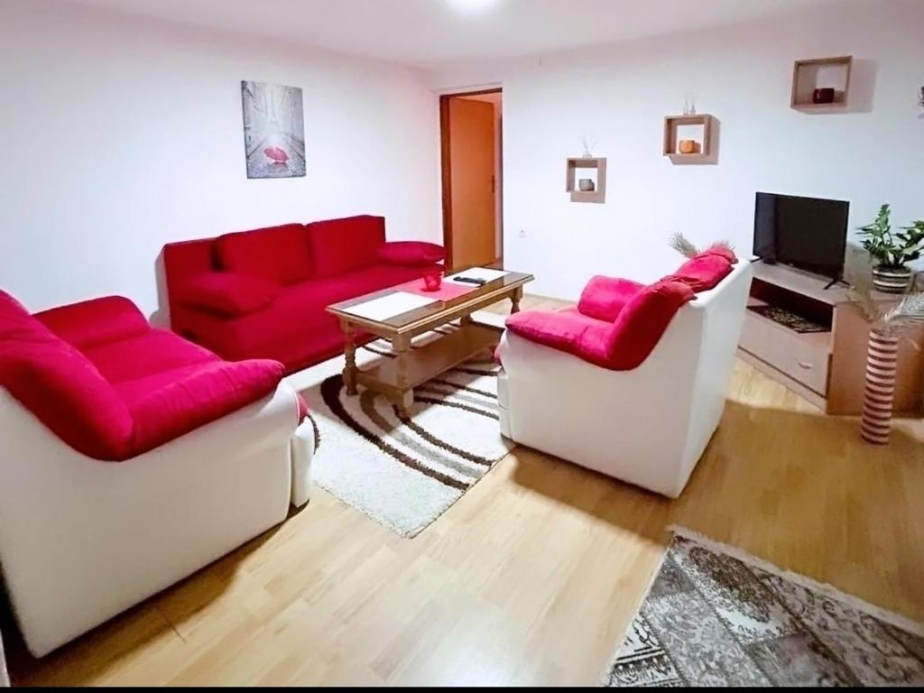 salon z 2 czerwonymi kanapami i telewizorem w obiekcie Apartman 053 w mieście Doboj