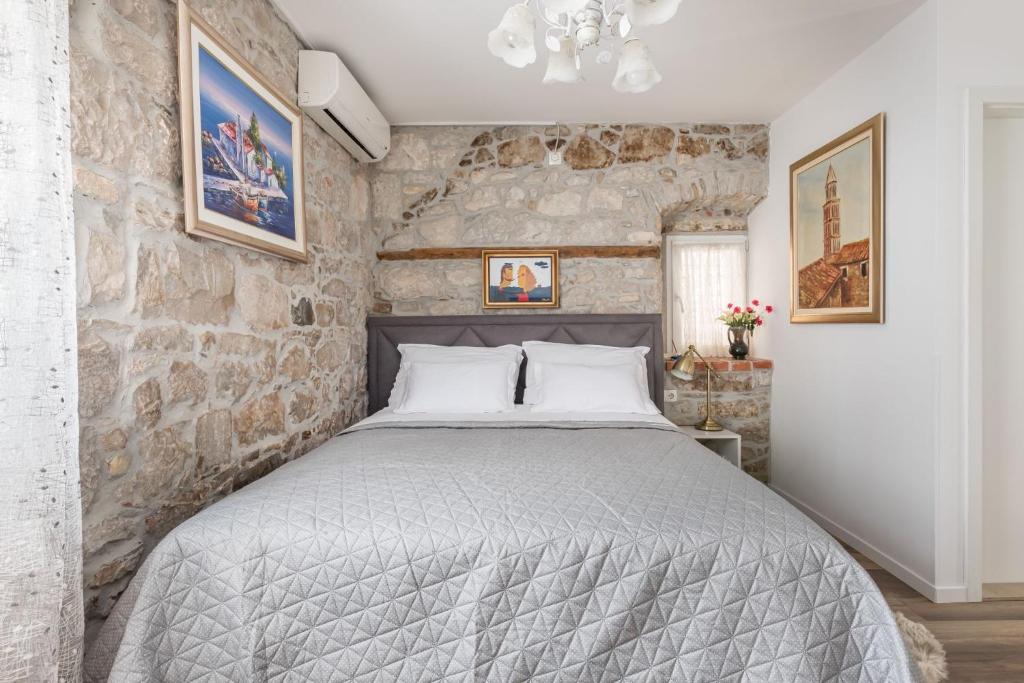 1 dormitorio con 1 cama grande en una pared de piedra en Apartments and Rooms Petra, en Split