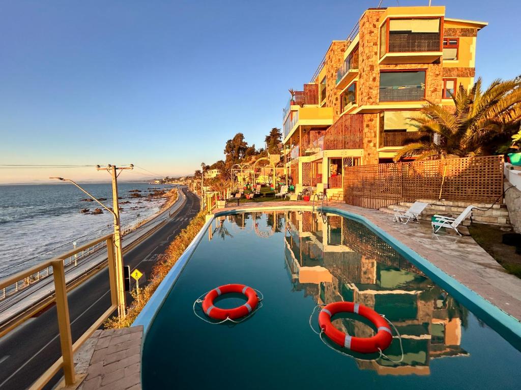 una piscina accanto a una spiaggia con due barche rosse di Pacificsunset Concón a Valparaíso