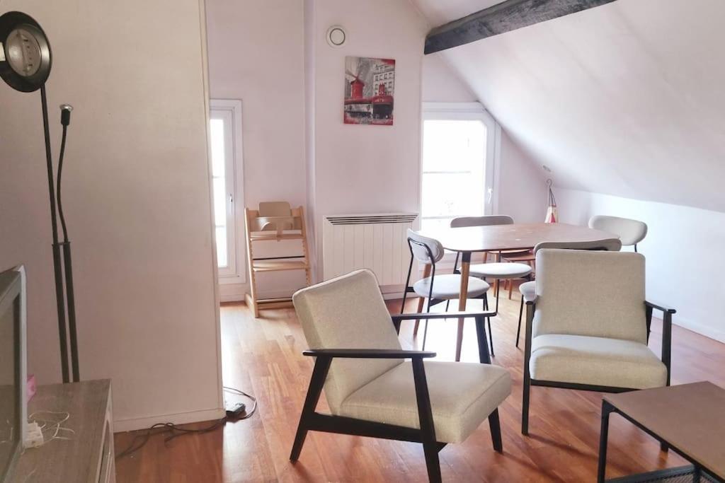 sala de estar con sillas, mesa y reloj en 3 pièces atypique 63m2, proche centre de Paris., en Les Lilas